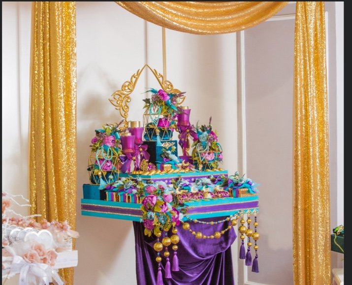 Intricate gold sequin drapes with purple and peacock floral arrangement