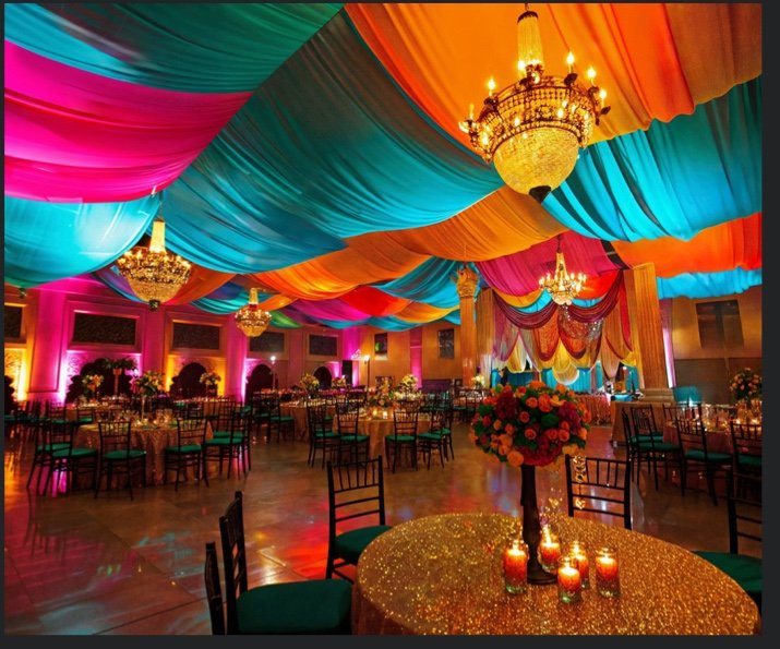 Vibrant engagement and sangeet hall with ceiling drapes and lighting